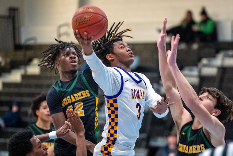 Roman Catholic’s Tyler Sutton scores on a drive over Lansdale Catholic’s Yeboa Cobbald Jr. (left) and Carey Romero during a Catholic League game at Holy Family University on Jan. 5.