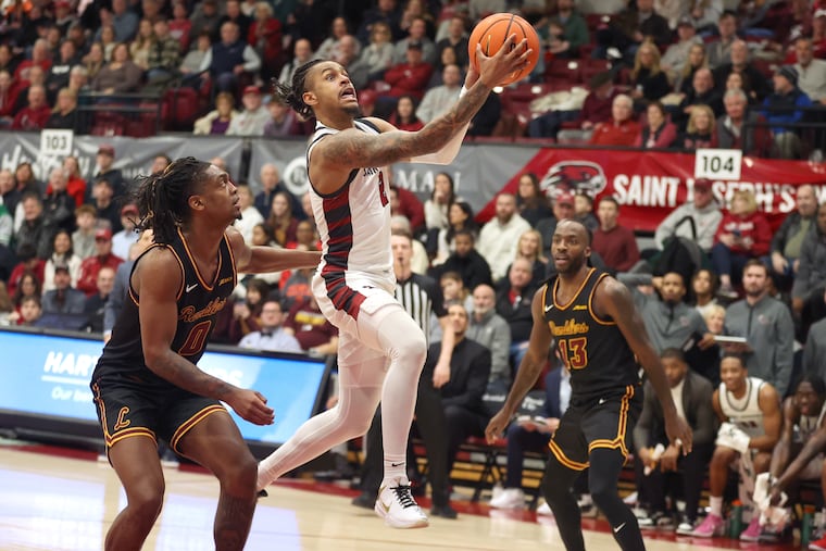 Erik Reynolds, center, of St. Joseph's goes up for a shot between Des Watson, left, and Sheldon Edwards of  Loyola Chicago during the 2nd half  on Jan. 11, 2025.