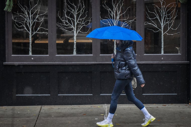 A pedestrian walks in the rain on Spruce near Camac Streets. It will about 30 degrees colder on Thursday.