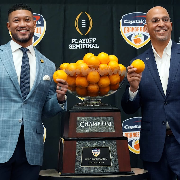 Notre Dame head coach Marcus Freeman, left, and Penn State head coach James Franklin pose with the Orangle Bowl trophy during a news conference.