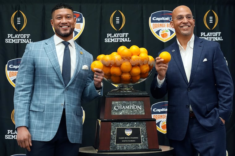 Notre Dame head coach Marcus Freeman, left, and Penn State head coach James Franklin pose with the Orangle Bowl trophy during a news conference.