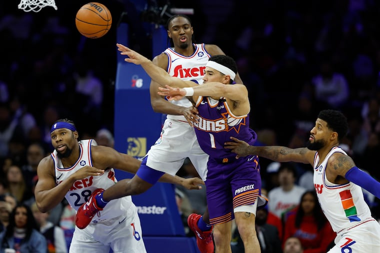 Suns guard Devin Booker passes the basketball past Sixers guard Tyrese Maxey, forward’s Guerschon Yabusele (left) and Paul George in the fourth quarter.