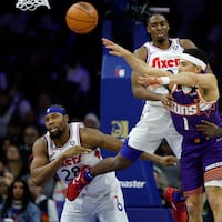 Suns guard Devin Booker passes the basketball past Sixers guard Tyrese Maxey, forward’s Guerschon Yabusele (left) and Paul George in the fourth quarter.