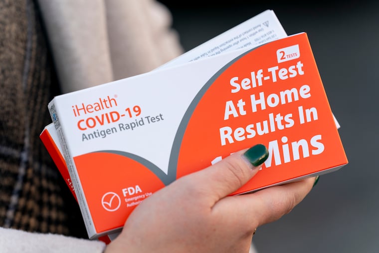 A woman holds two boxes of at-home COVID-19 test kits in Washington on Dec. 22, 2021.