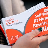 A woman holds two boxes of at-home COVID-19 test kits in Washington on Dec. 22, 2021.