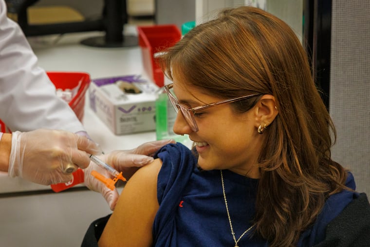 Alexandra Pompan, a customer service associate, gets vaccinated against COVID-19 by Dr. Philip Maceno, pharmacy manager at Walgreens, on Monday, October 23, 2023.