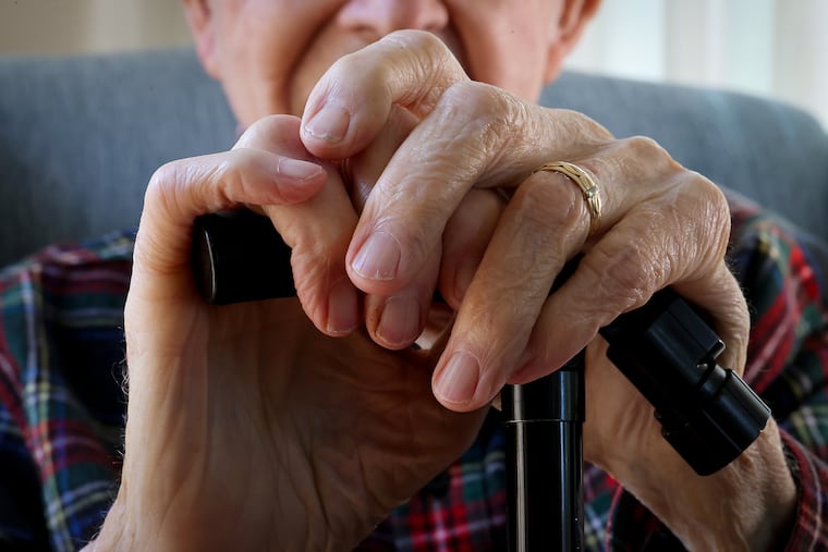 Charles Malloy, 99, rests his hands on his cane as he poses for a portrait at his home in West Chester on Wednesday, April 24, 2024.