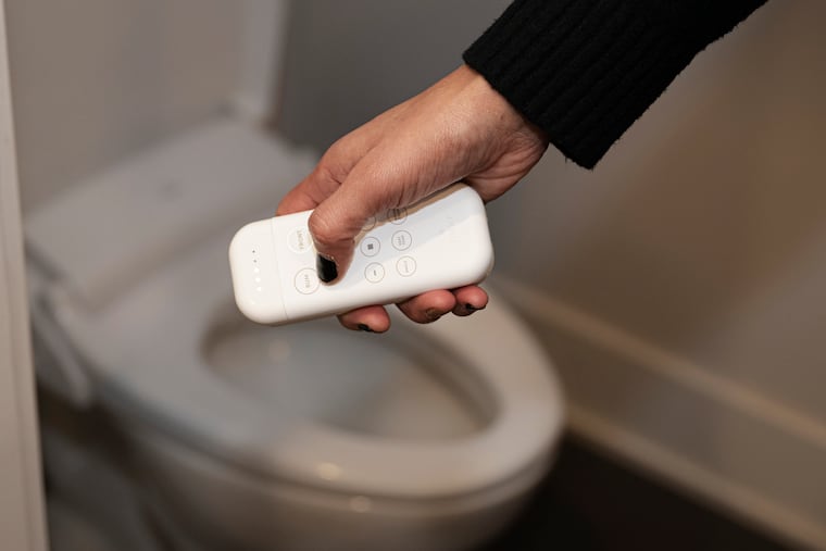 Samaya Brown holds a remote control for her upgraded toilet that features seat and water temperature control.