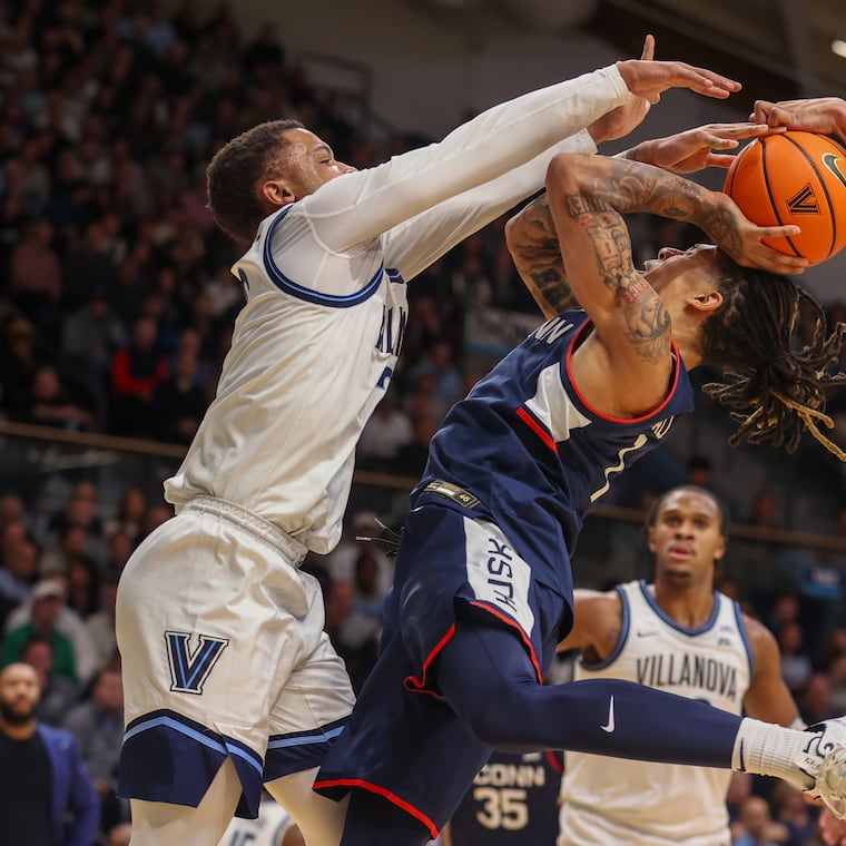 UConn’s Solo Ball gets his shot blocked by Villanova’s Jhamir Brickus (left) and Tyler Perkins (right) in the first half.