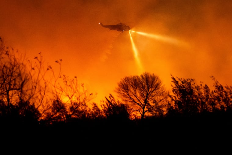 A helicopter drops water while fighting the Auto Fire in Ventura County, Calif., on Monday, Jan. 13, 2025.