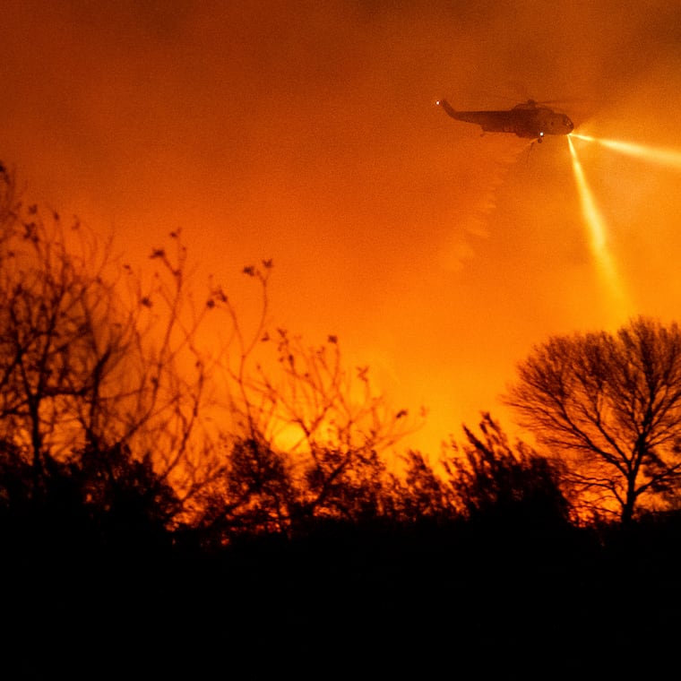 A helicopter drops water while fighting the Auto Fire in Ventura County, Calif., on Monday, Jan. 13, 2025.