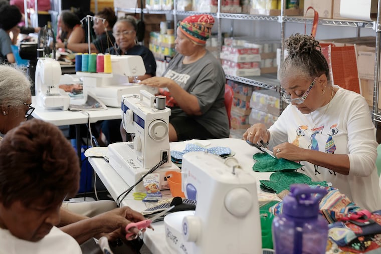 Pan African Sisterhood Health Initiative (P.A.S.H.I.) volunteer Gail Hoffman (right) makes pads with other volunteers at the Ujima Friends Peace Center in Philadelphia on Wednesday, June 12, 2024.