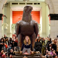 An 8-year-old waits under the John Wanamaker Eagle for the start of Macy's "Christmas Pageant of Lights" in 2019.