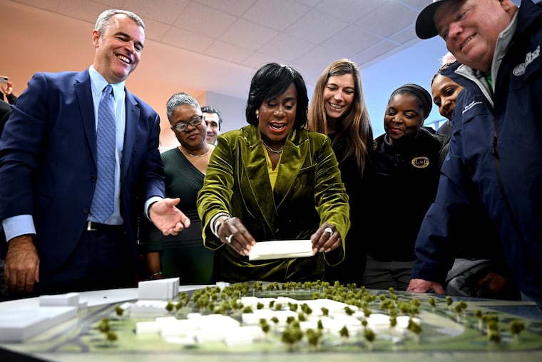 Mayor Cherelle L. Parker places a new block on the scale model of the Riverview Wellness Village Wednesday, Jan. 8, 2025 during the unveiling of Philadelphia’s new city-operated drug treatment facility. At left is Managing Director Adam Thiel and Councilmember Michael Driscoll is at right.